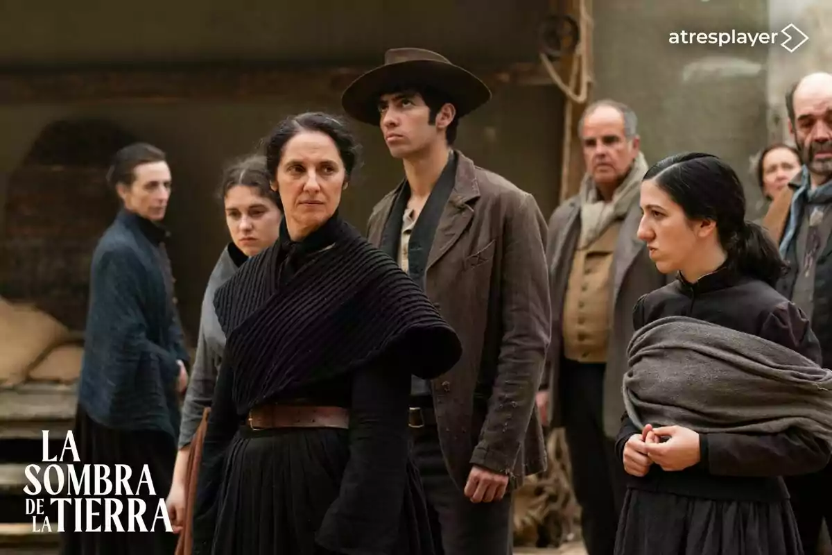 Personas vestidas con ropa de época, con expresiones serias, en una escena de la serie "La Sombra de la Tierra" de Atresplayer.