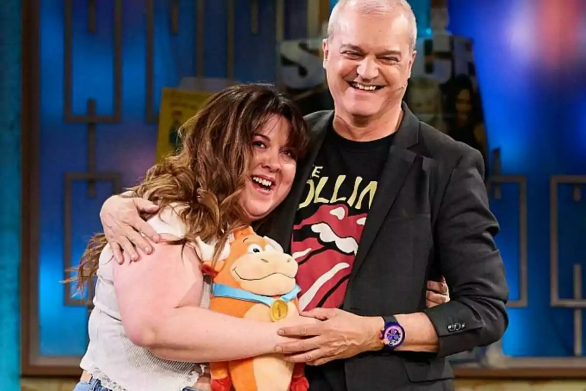Lalachus y Ramón García sonríen mientras se abrazan en La Revuelta, ella sostiene un peluche y él lleva una camiseta con un diseño llamativo. Lalachus y Ramón García sonríen mientras se abrazan en La Revuelta, ella sostiene un peluche y él lleva una camiseta con un diseño llamativo.