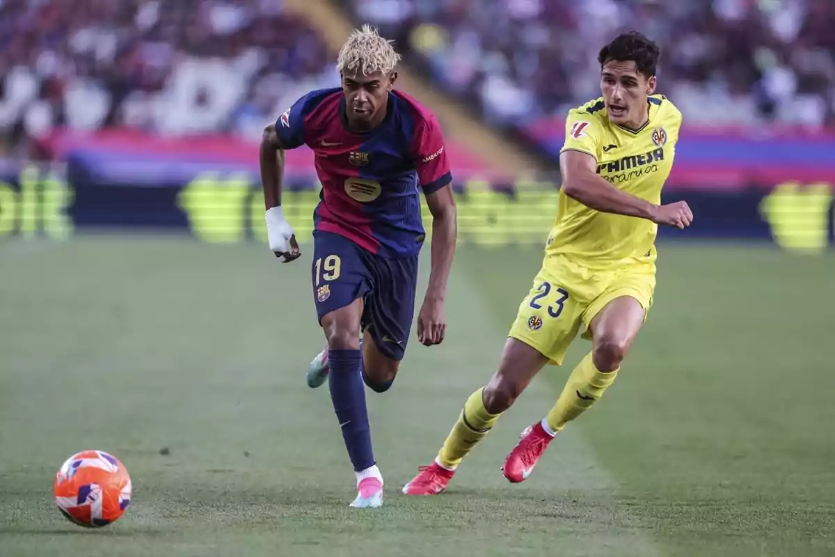 Dos jugadores de fútbol compiten por el balón en un partido, uno viste uniforme azul y rojo y el otro amarillo. Dos jugadores de fútbol compiten por el balón en un partido, uno viste uniforme azul y rojo y el otro amarillo.