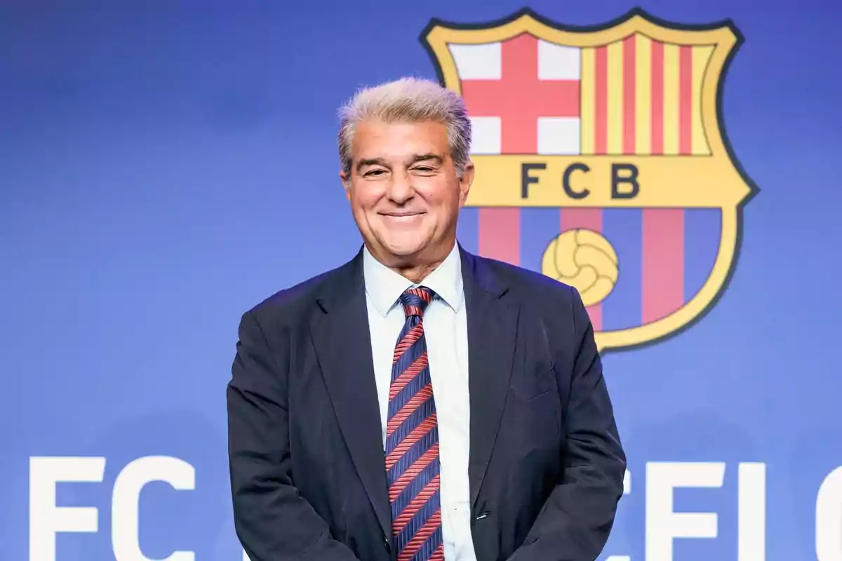 Hombre de traje y corbata frente a un logotipo del FC Barcelona.