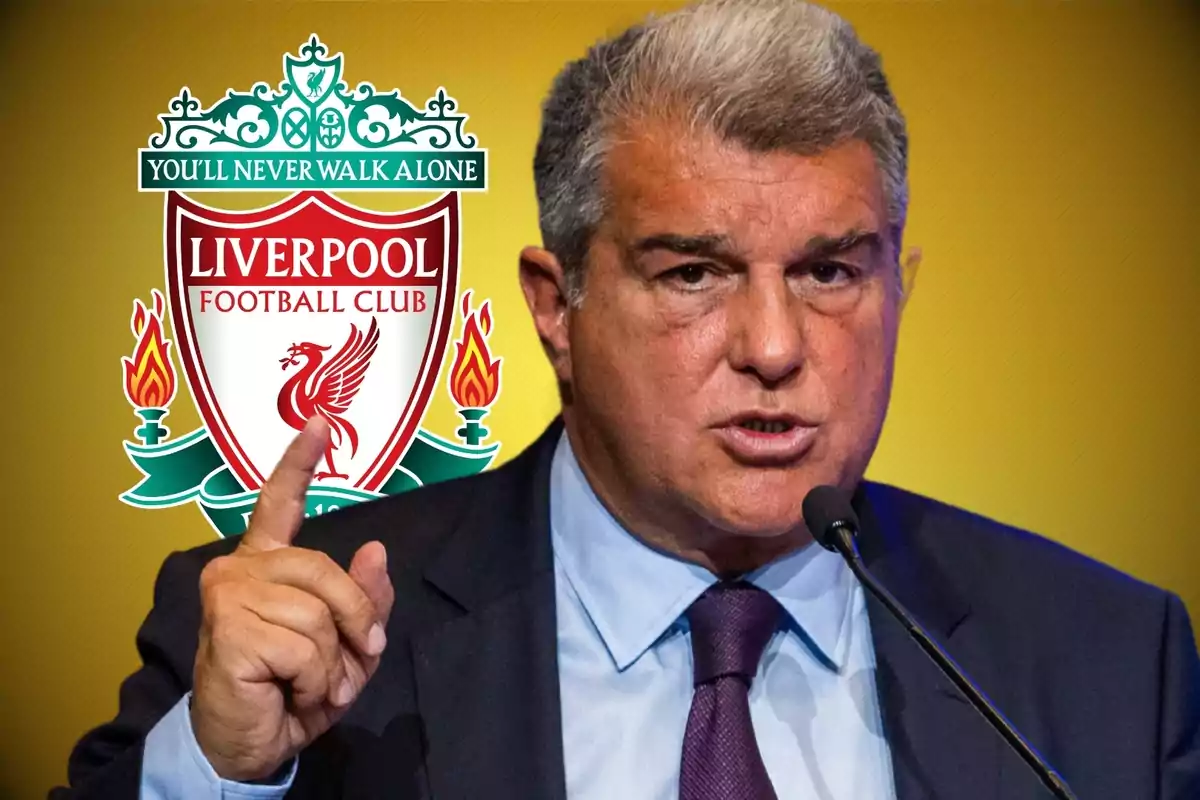 Un hombre hablando en un micrófono con el escudo del Liverpool Football Club de fondo.