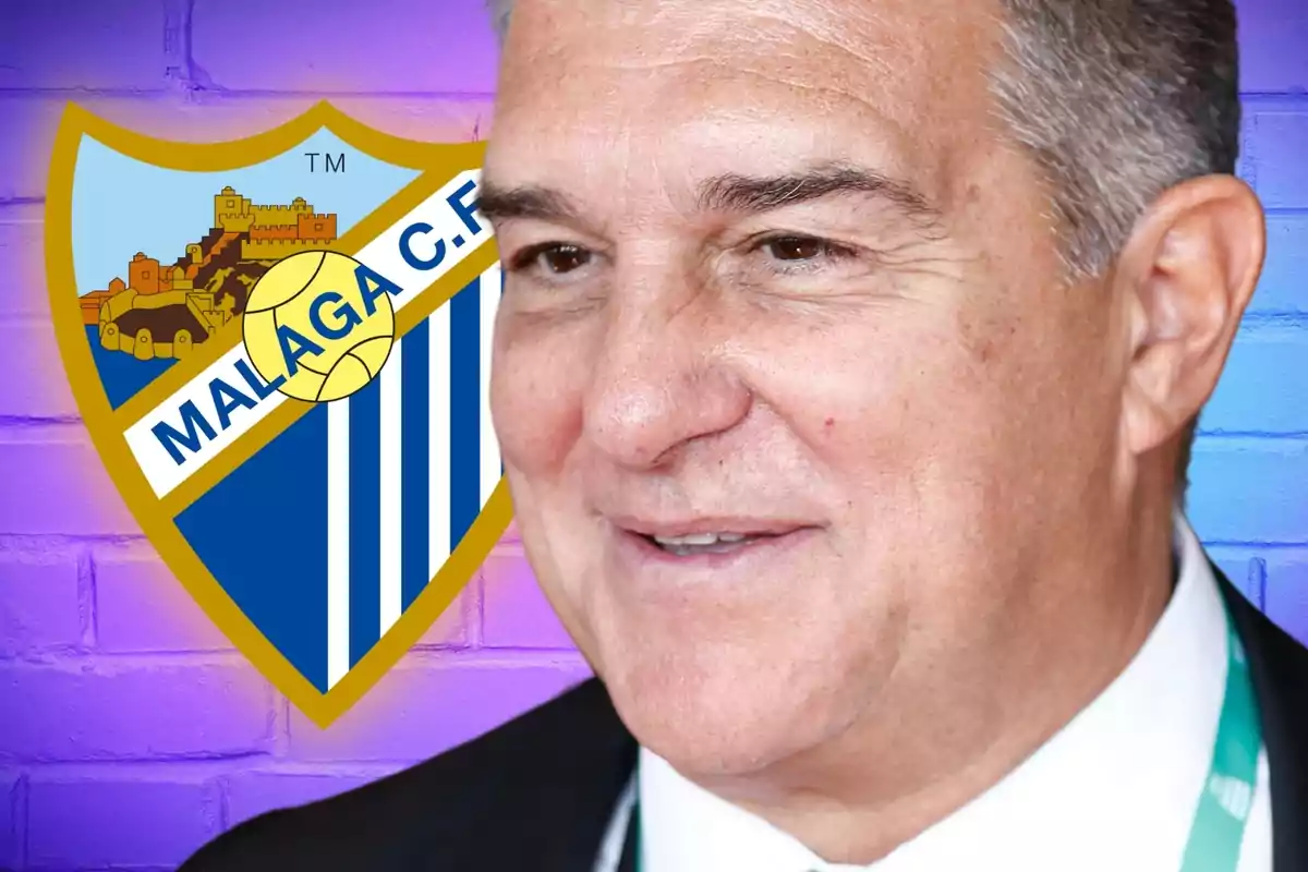 Un hombre sonriente con canas y traje, con el escudo del Málaga C.F. de fondo.