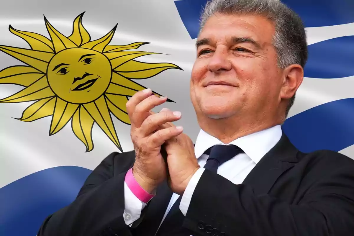 Hombre de traje aplaudiendo frente a una bandera con un sol sonriente.