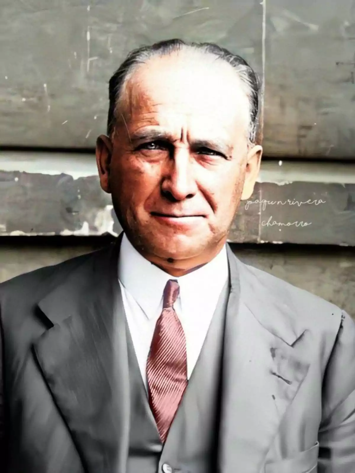 Un hombre mayor con traje y corbata, de cabello canoso, posando frente a un fondo gris. Un hombre mayor con traje y corbata, de cabello canoso, posando frente a un fondo gris.