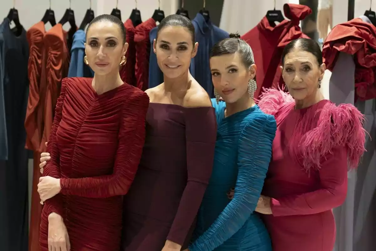 Vicky Martín Berrocal, Rocío Martín Berrocal, Victoria Martín Serrano y Alba Díaz Martín posan juntas en un evento de moda, vistiendo elegantes vestidos de diferentes colores y texturas, con perchas de ropa en el fondo en Las Berrocal.