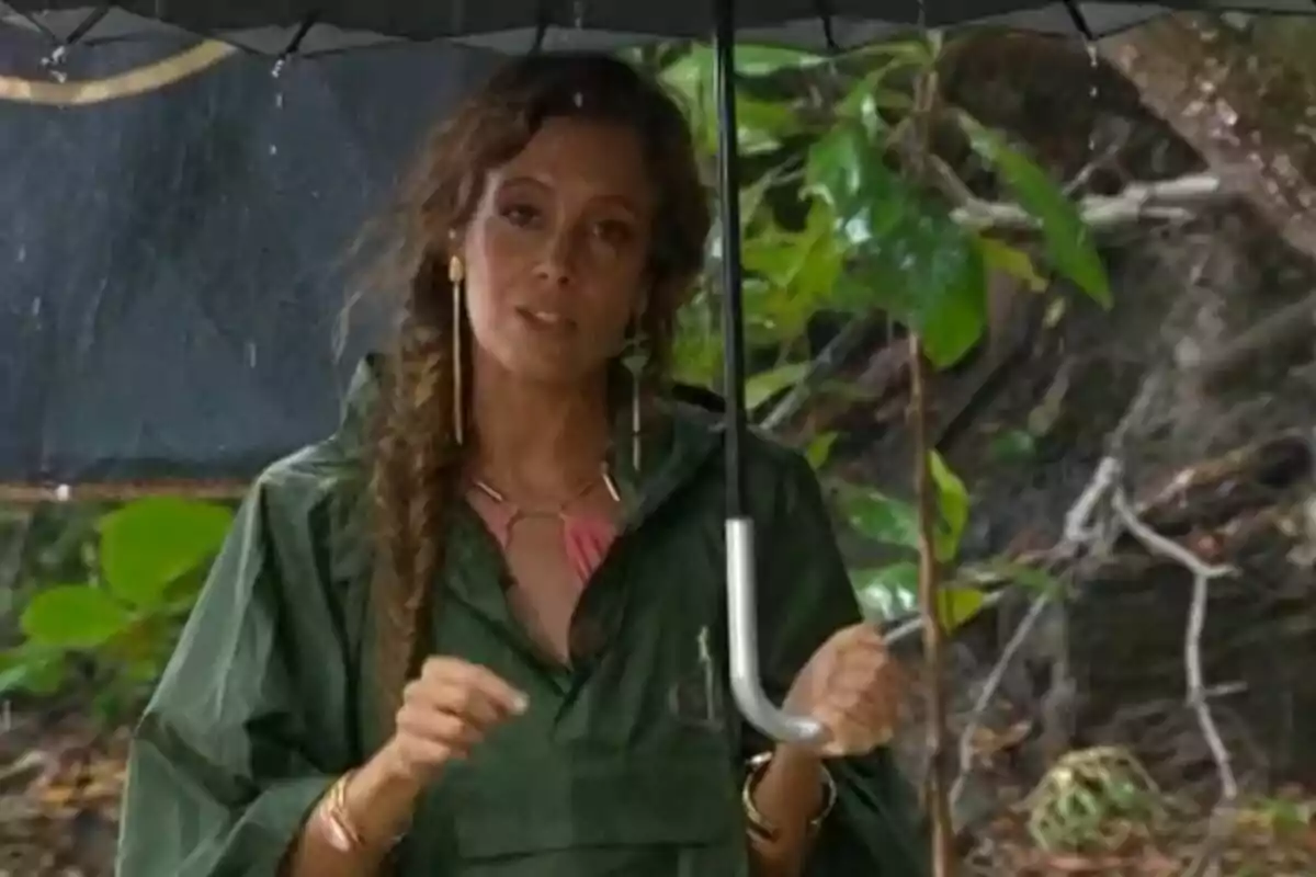 Captura de Laura Madrueño bajo la lluvia sosteniendo un paraguas y vistiendo una chubasquero verde en Supervivientes