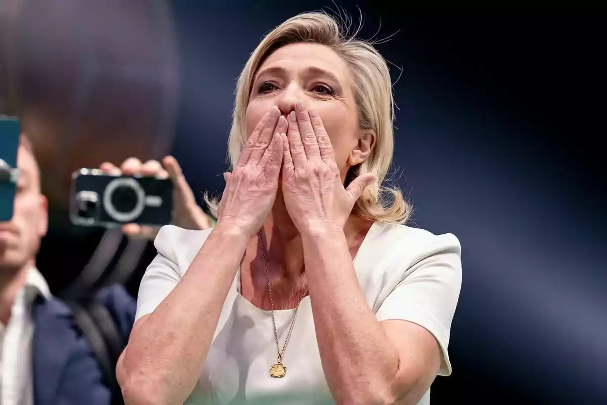 Plano medio de Marine Le Pen con las manos en la boca lanzando besos a los asistentes de un mitin