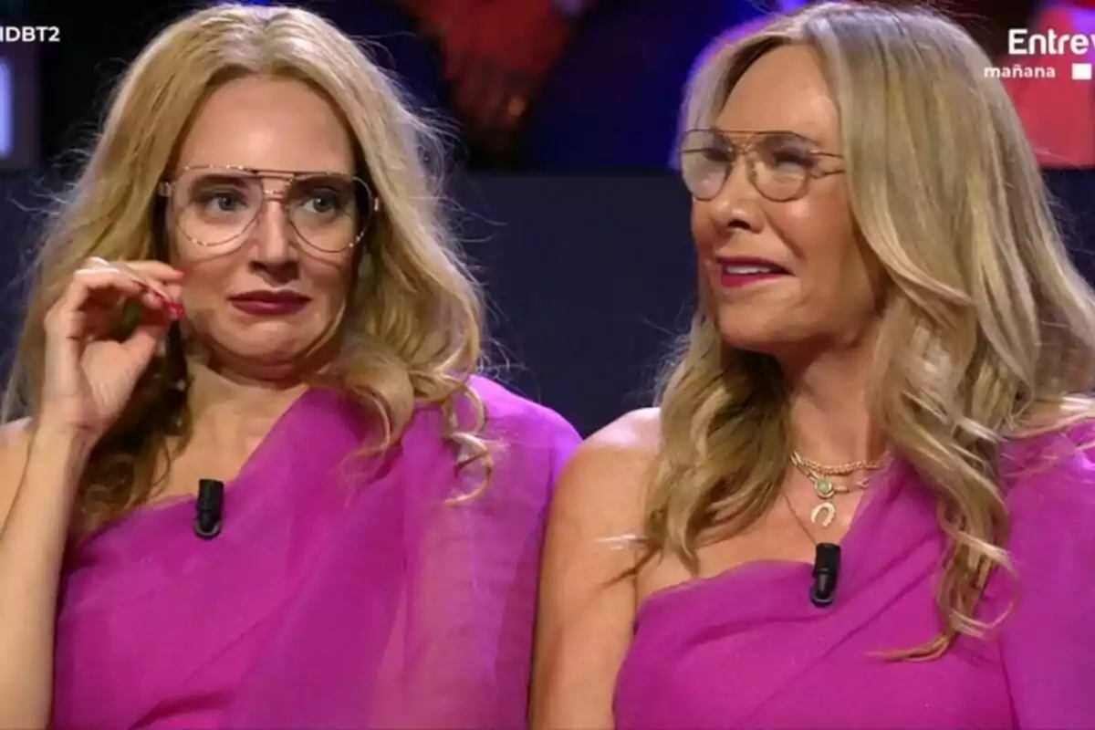 Belén Rodríguez junto a Leonor Lavado caracterizada con vestidos y telas de color rosa, ambas con gafas y cabello rubio, están sentadas una al lado de la otra en el plató de Gran Hermano.