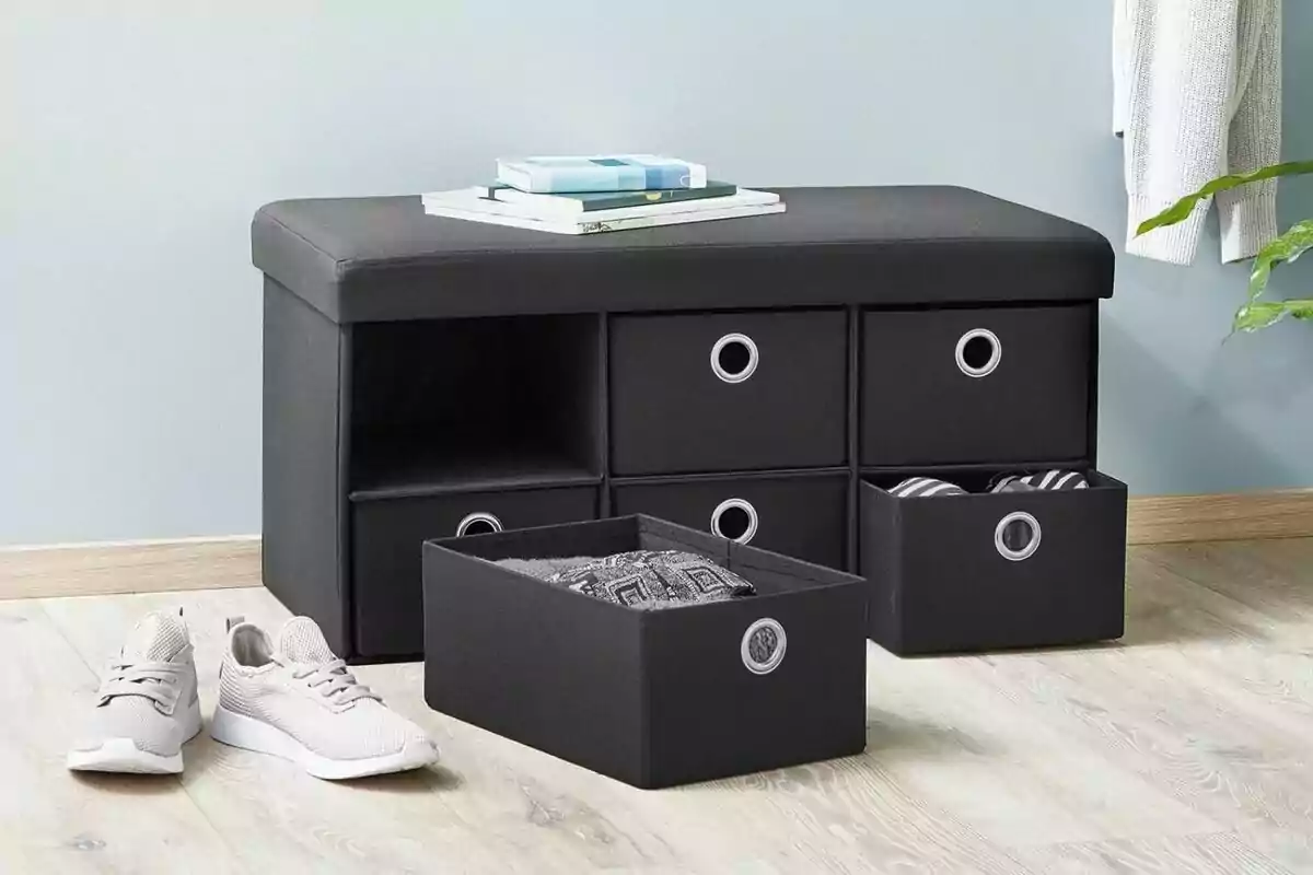Banco de almacenamiento negro con cajones y zapatos deportivos blancos sobre un suelo de madera clara. Banco de almacenamiento negro con cajones y zapatos deportivos blancos sobre un suelo de madera clara.