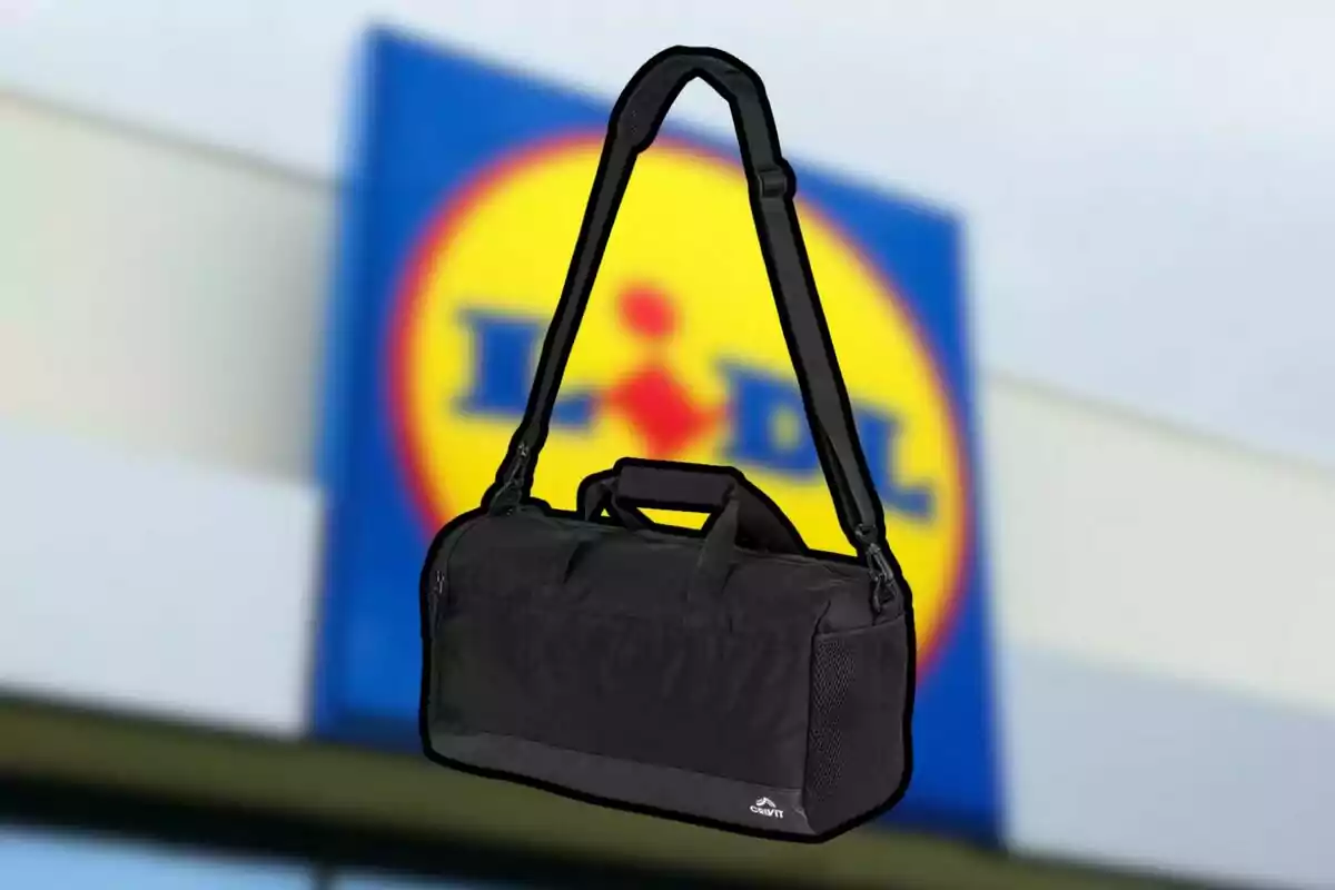 Una bolsa de deporte negra con correa ajustable frente a un fondo desenfocado de un logotipo de supermercado. Una bolsa de deporte negra con correa ajustable frente a un fondo desenfocado de un logotipo de supermercado.