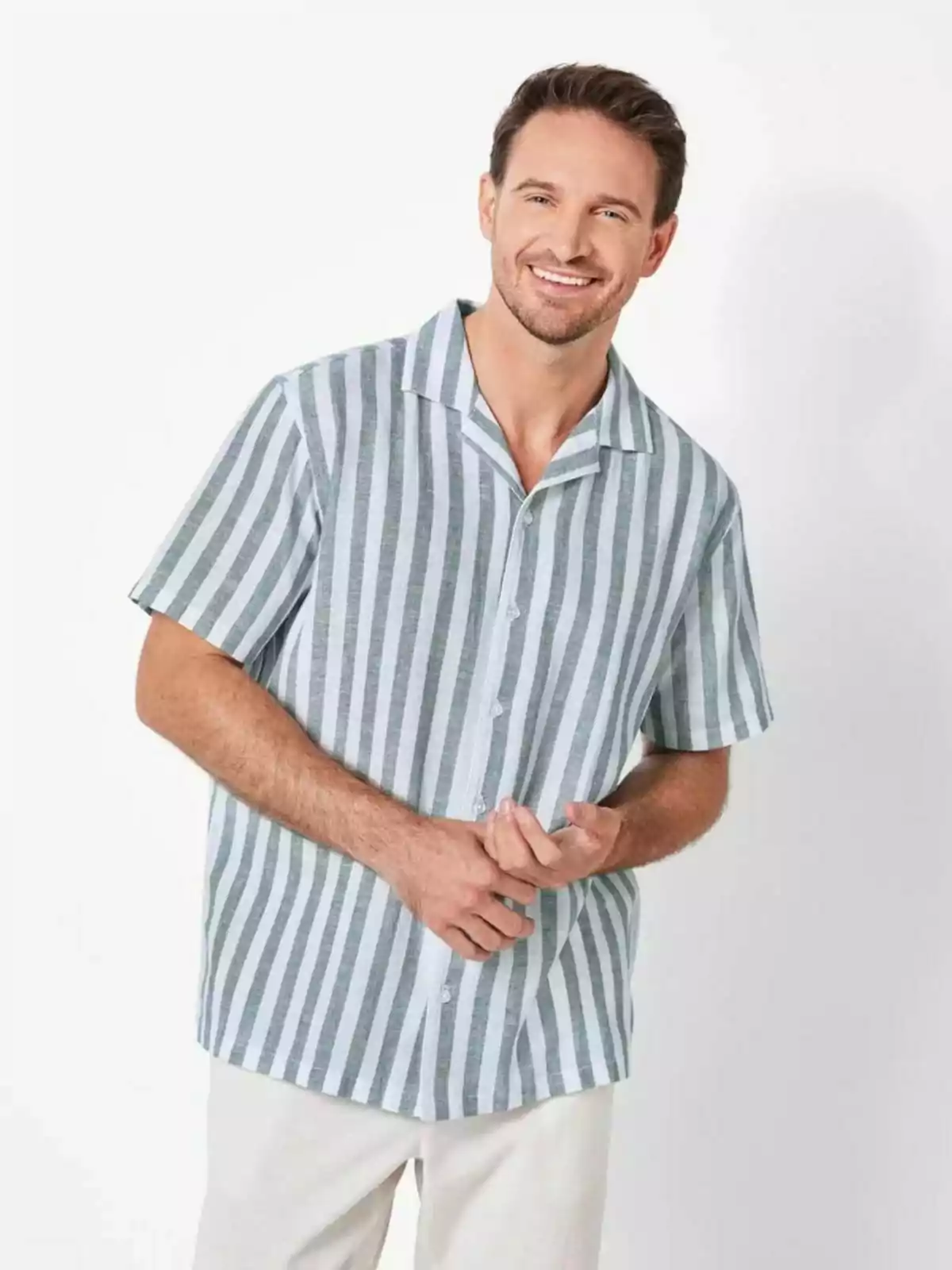 Hombre sonriendo con camisa de rayas verticales y pantalones claros. Hombre sonriendo con camisa de rayas verticales y pantalones claros.