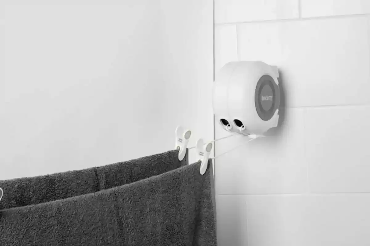 Dispositivo de cuerda retráctil montado en la pared con una toalla gris colgada. Dispositivo de cuerda retráctil montado en la pared con una toalla gris colgada.