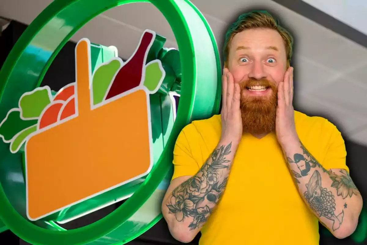 Hombre con barba y tatuajes sonríe sorprendido frente a un letrero de supermercado con frutas y una botella