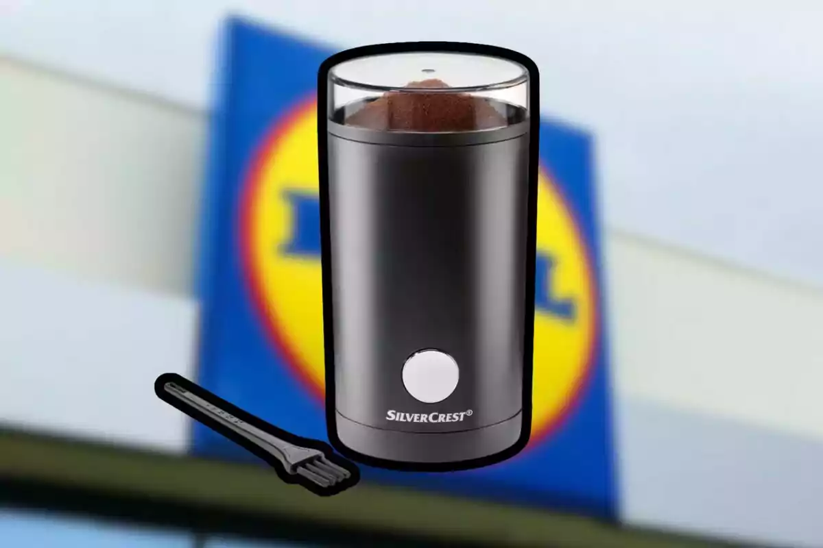 Molinillo de café eléctrico SilverCrest de color negro con un cepillo pequeño de limpieza frente a un cartel borroso de una tienda Lidl Molinillo de café eléctrico SilverCrest de color negro con un cepillo pequeño de limpieza frente a un cartel borroso de una tienda Lidl