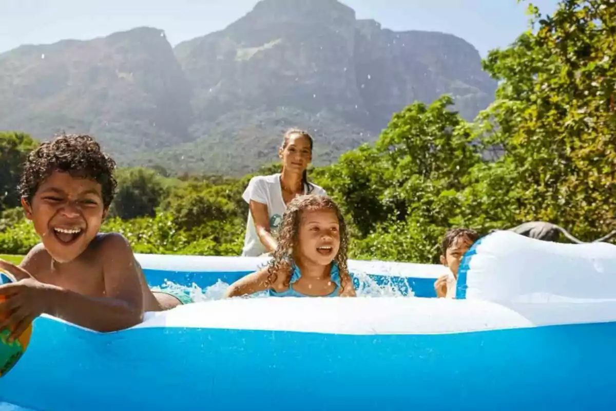 Un grupo de niños juega y se divierte en una piscina inflable al aire libre con montañas y vegetación de fondo. Un grupo de niños juega y se divierte en una piscina inflable al aire libre con montañas y vegetación de fondo.