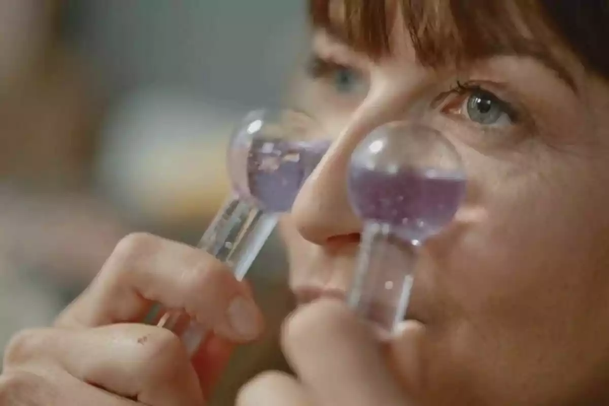 Mujer sosteniendo dos esferas de cristal con líquido morado cerca de sus ojos. Mujer sosteniendo dos esferas de cristal con líquido morado cerca de sus ojos.