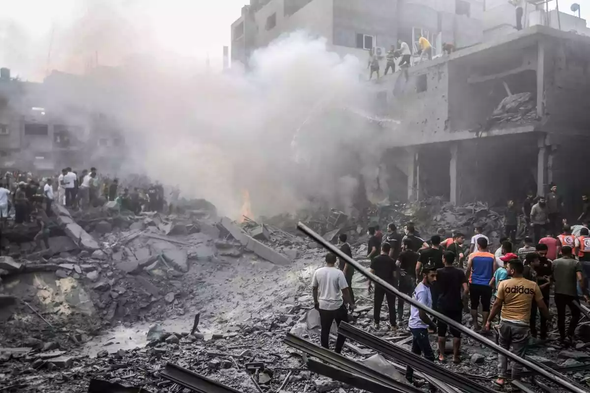 La gente apaga un incendio en el lugar de los ataques aéreos israelíes mientras continúan los combates entre las tropas israelíes y los militantes islamistas de Hamas.