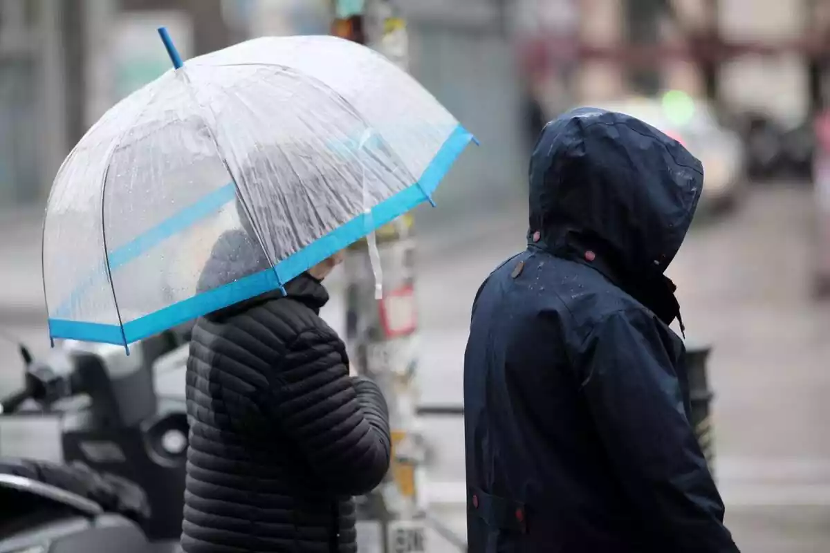 Dos personas abrigadas se protegen de la lluvia con un paraguas