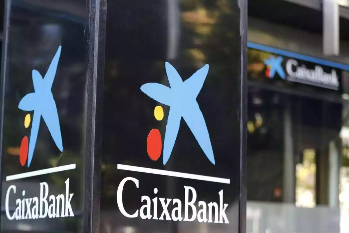 Poste exterior con el logo de CaixaBank delante del mismo banco