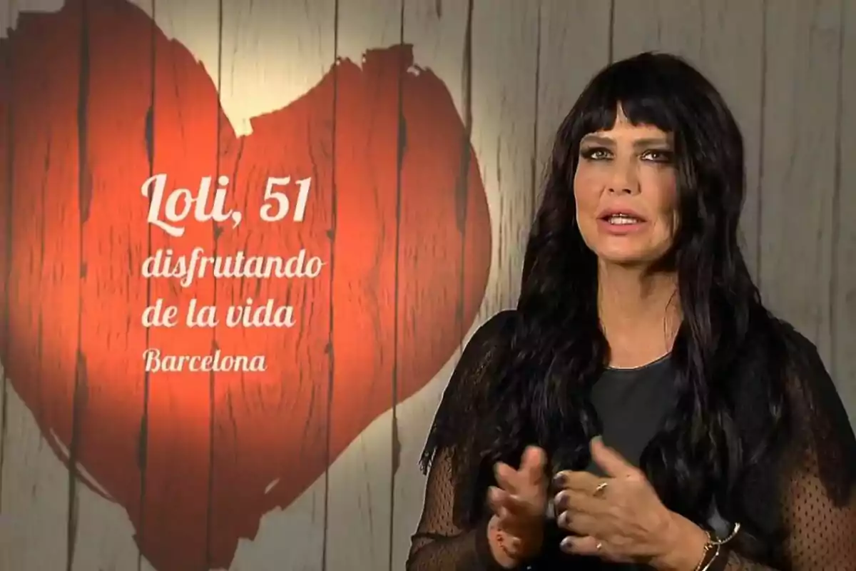 Loli Sánchez de cabello largo y oscuro con vestido negro hablando frente a una pared de madera clara con un gran corazón rojo y texto que dice Loli 51 disfrutando de la vida Barcelona en First Dates Loli Sánchez de cabello largo y oscuro con vestido negro hablando frente a una pared de madera clara con un gran corazón rojo y texto que dice Loli 51 disfrutando de la vida Barcelona en First Dates