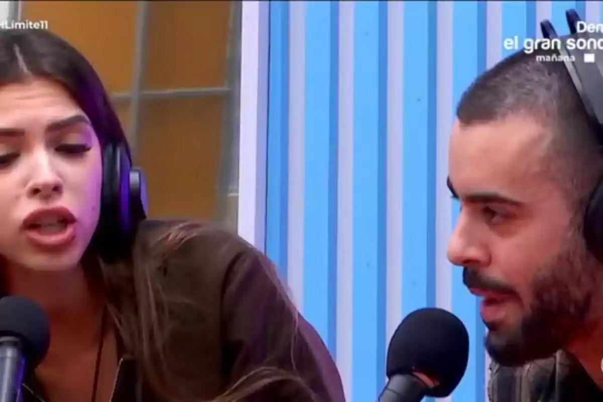 Lucía Rolek y Ruvens con auriculares hablando frente a micrófonos en un estudio con fondo de rayas azules en Gran Hermano.