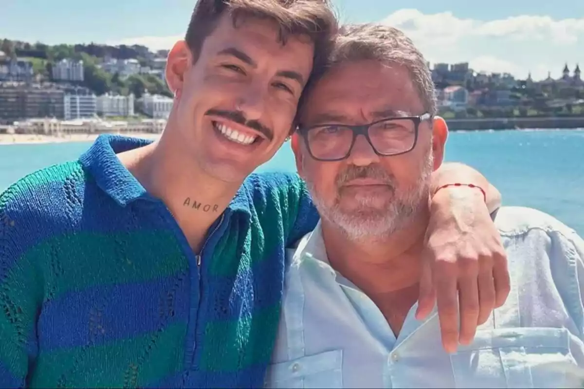 Luitingo junto a su padre Sele de Triana sonrientes posando juntos frente al mar con una ciudad al fondo.