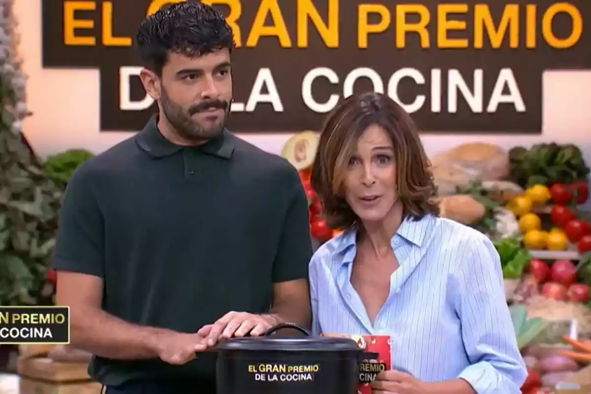 Lydia Bosch y Germán González en un set de televisión con el letrero "El Gran Premio de la Cocina" en el fondo.