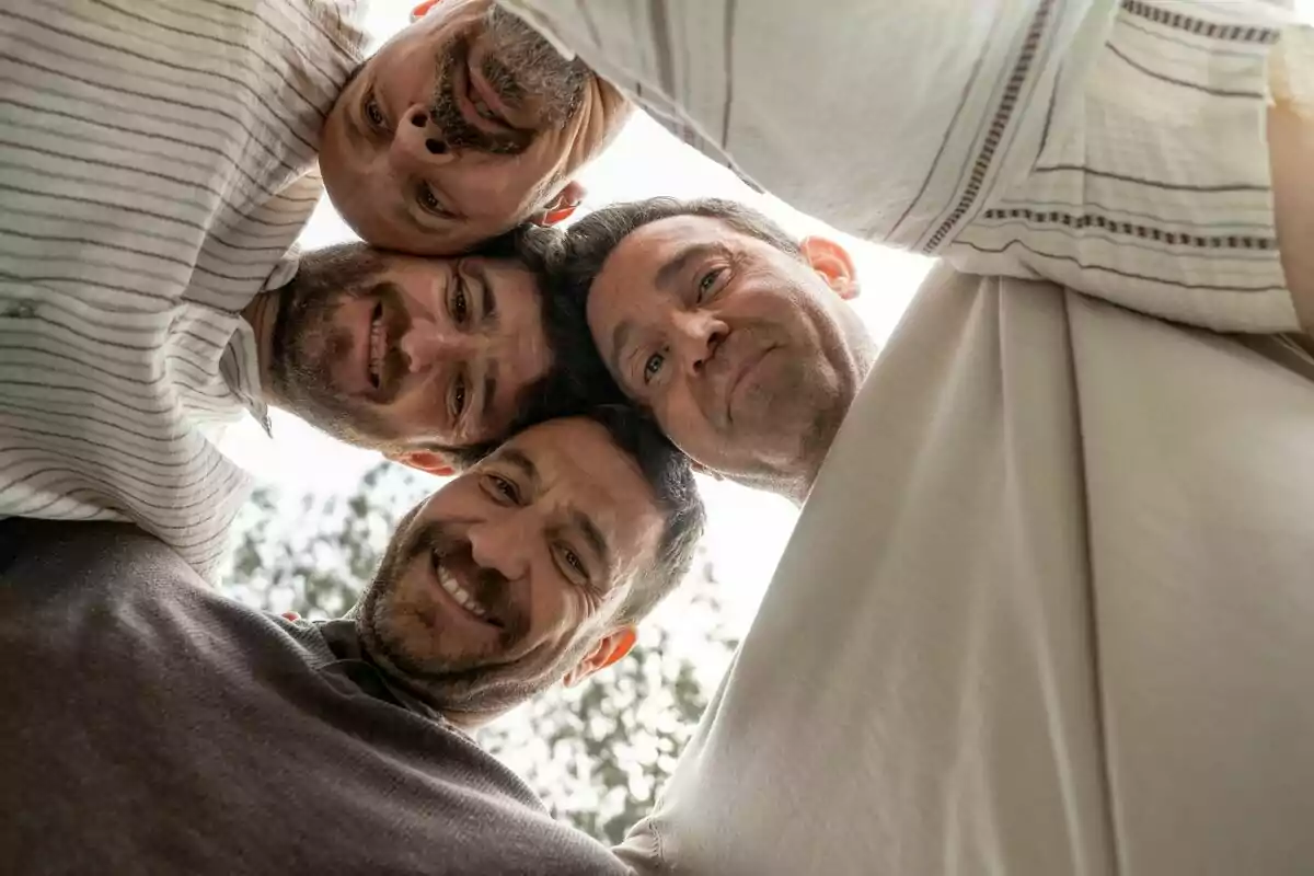 Fernando Gil, Raúl Tejón, Gorka Otxoa y Fele Martínez sonrientes miran hacia abajo en un círculo, vistos desde una perspectiva inferior en Machos Alfa.