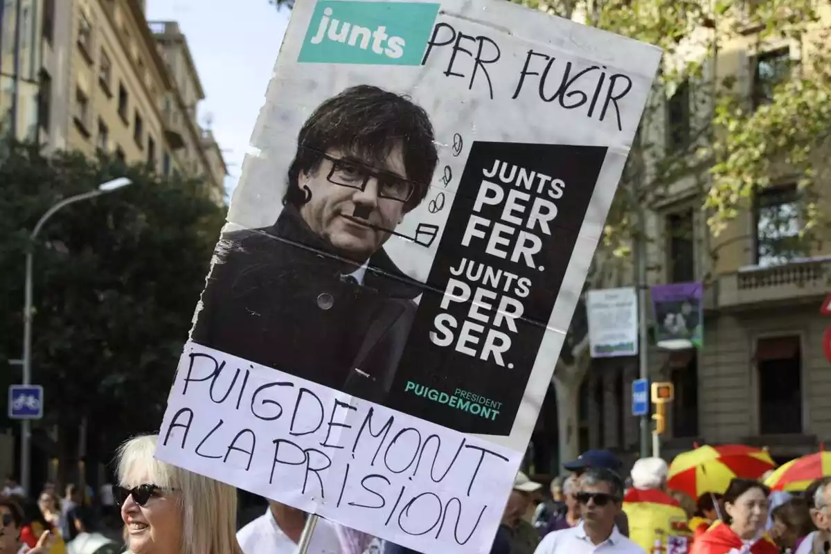 Primer plano de una pancarta en la manifestación contra la amnistía con el lema 'Junts per fugir, Puigdemont a prisión'