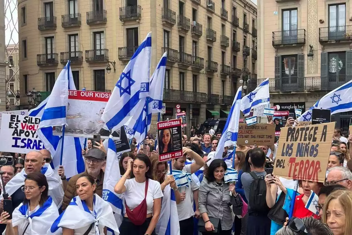Varios manifestantes en la plaza de Sant Jaume de Barcelona luciendo banderas de Israel y pancantas con los rostros de algunos de los secuestrados por Hamás