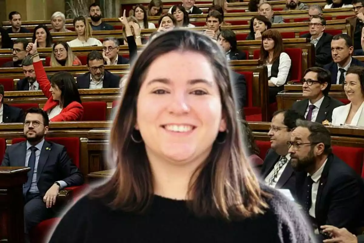 Una mujer sonriente en primer plano con una audiencia en un parlamento de fondo.