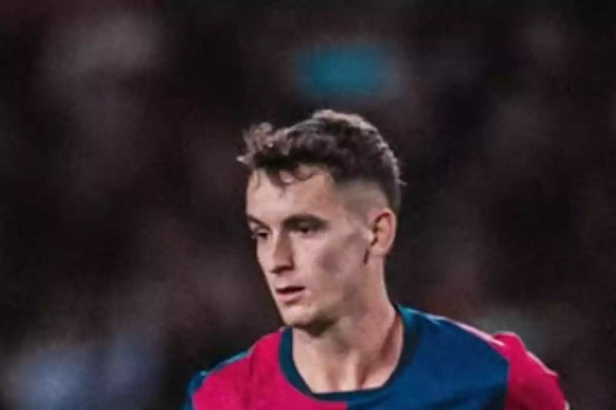 Un jugador de fútbol con uniforme azul y rojo en un campo de juego. Un jugador de fútbol con uniforme azul y rojo en un campo de juego.
