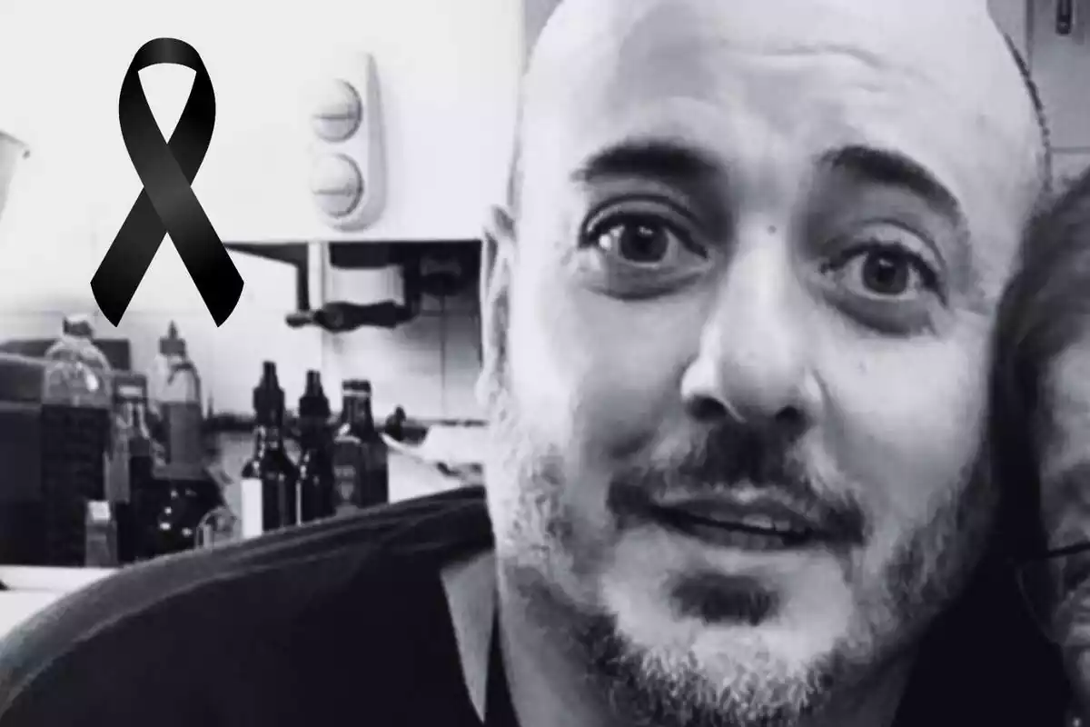 Primer plano de Marc Redondo, jefe de cocina del Celler de Can Roca, con rostro medio sonriente, en una foto en blanco y negro con un lazo negro al lado