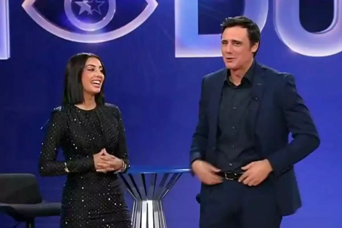 Ion Aramendi y Marieta Díaz sonríen en un escenario con fondo azul y un logotipo de ojo de GH DÚO.