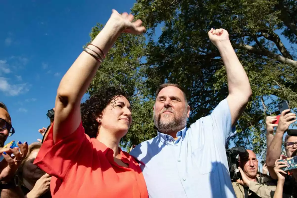 Marta Rovira y Oriol Junqueras levantando los brazos en un evento al aire libre.