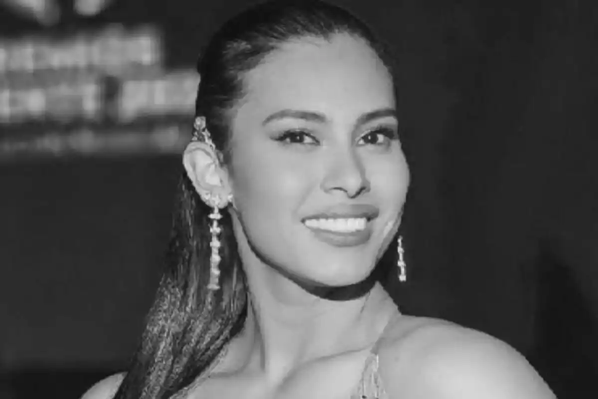 Fotografía en blanco y negro de Maryan Gómez sonriente con aretes largos y el cabello recogido.