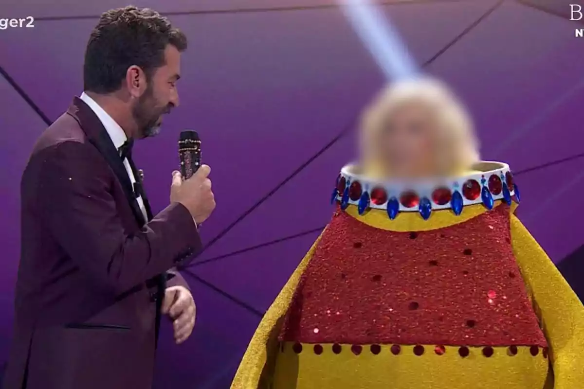 Arturo Valls con micrófono habla con una persona disfrazada de patito de goma con al cara difuminada en Mask Singer.