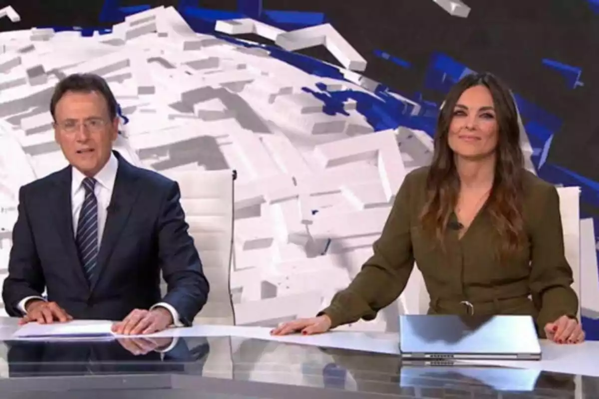 Matías Prats y Mónica Carrillo en Antena 3 Noticias sentados en un estudio de televisión con un fondo geométrico.