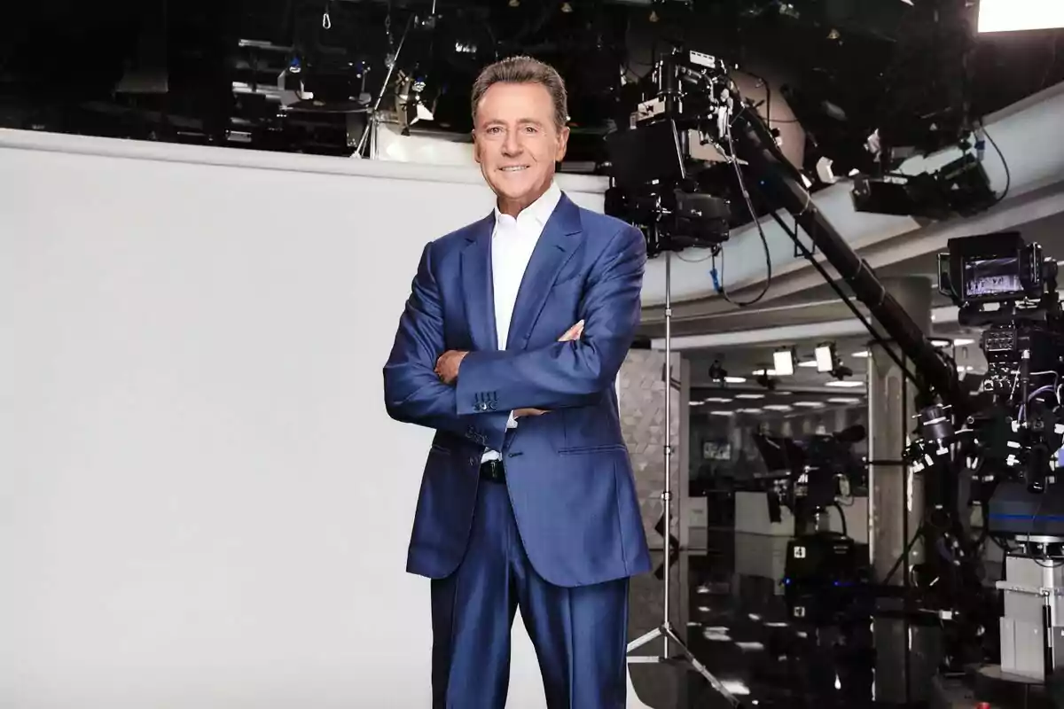 Matías Prats de pie con traje azul y camisa blanca, con los brazos cruzados, en un estudio de televisión rodeado de cámaras y equipo de grabación en Antena 3 Noticias. Matías Prats de pie con traje azul y camisa blanca, con los brazos cruzados, en un estudio de televisión rodeado de cámaras y equipo de grabación en Antena 3 Noticias.