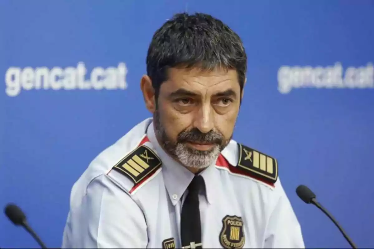 Un hombre con uniforme de policía en una conferencia de prensa frente a un fondo azul con el texto "gencat.cat".