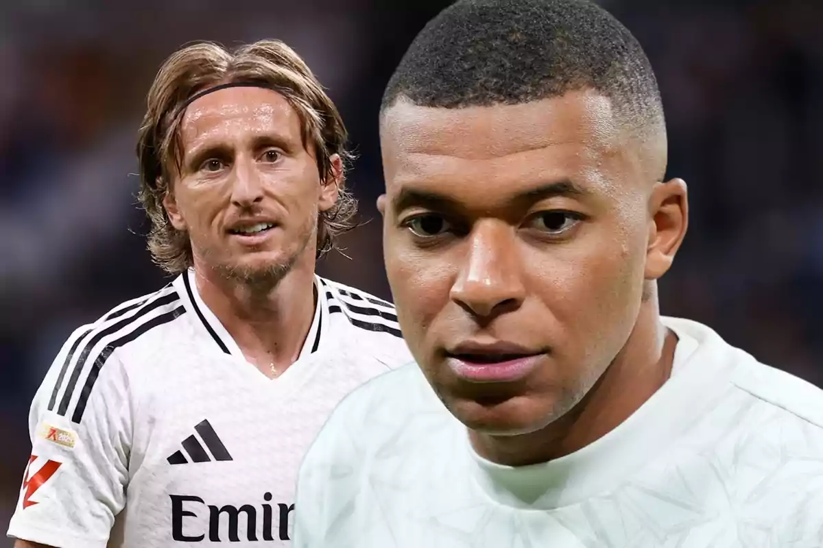 Dos futbolistas con uniforme blanco en un campo de juego uno de ellos lleva una camiseta del Real Madrid