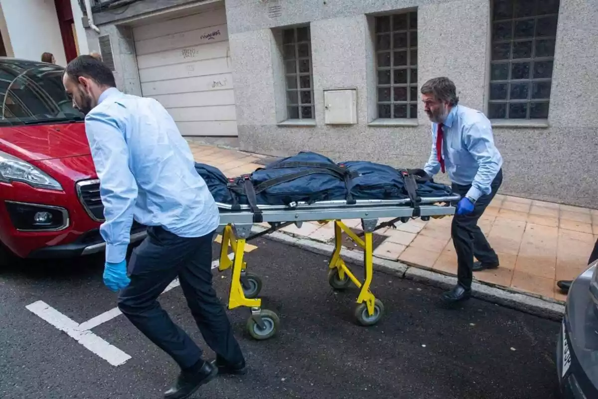 Dos médicos llevandose el cuerpo de una mujer en una camilla