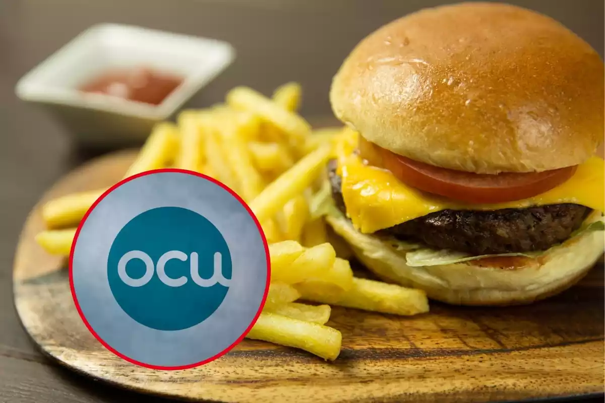 Logo de la OCU en un círculo rojo abajo a la izquierda sobre fondo de hamburguesa con patatas en una tabla de madera y un pequeño recipiente con ketchup al fondo desenfocado