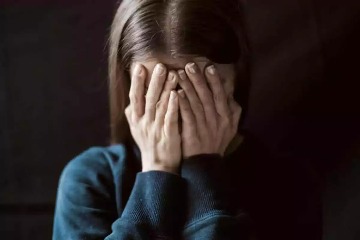 Persona cubriéndose el rostro con las manos en un gesto de angustia o tristeza.