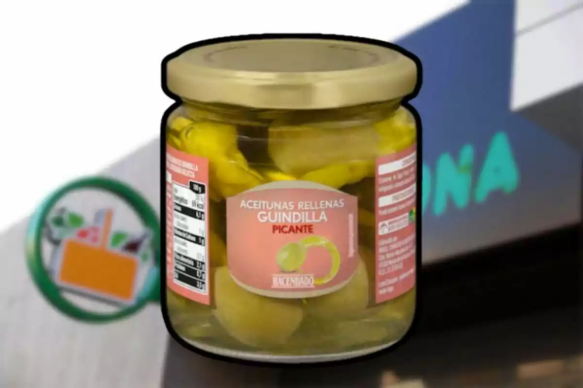 Un frasco de aceitunas rellenas de guindilla picante de la marca Hacendado frente a un fondo que parece ser un supermercado. Un frasco de aceitunas rellenas de guindilla picante de la marca Hacendado frente a un fondo que parece ser un supermercado.