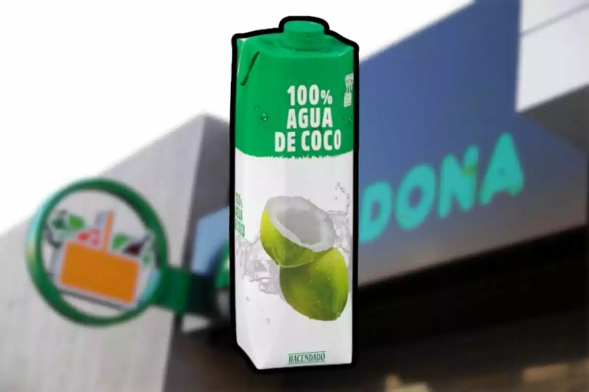 Envase de agua de coco de la marca Hacendado frente a una tienda Mercadona desenfocada. Envase de agua de coco de la marca Hacendado frente a una tienda Mercadona desenfocada.