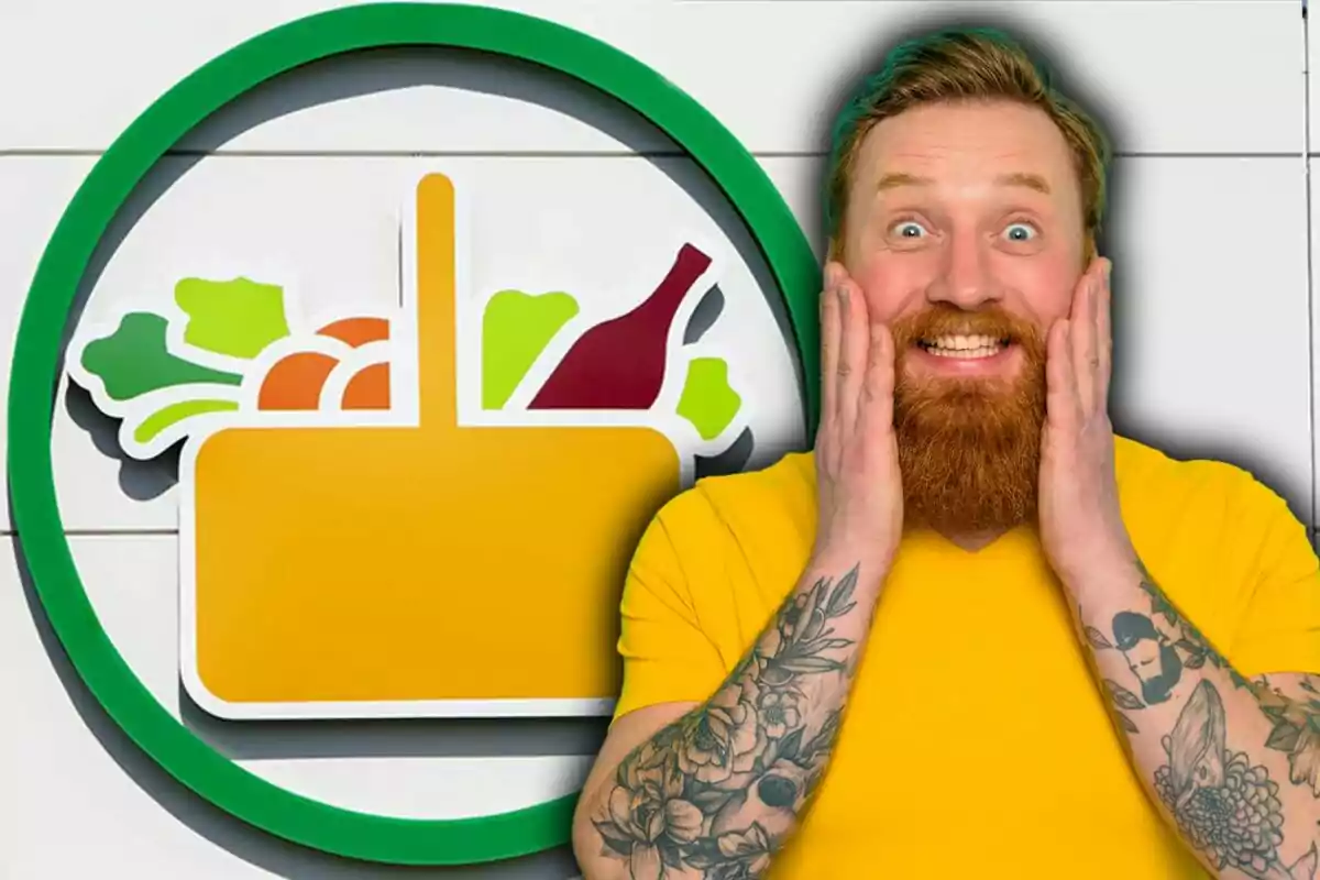 Hombre pelirrojo con barba y camiseta amarilla sonríe sorprendido frente a un logo de supermercado con verduras y una botella