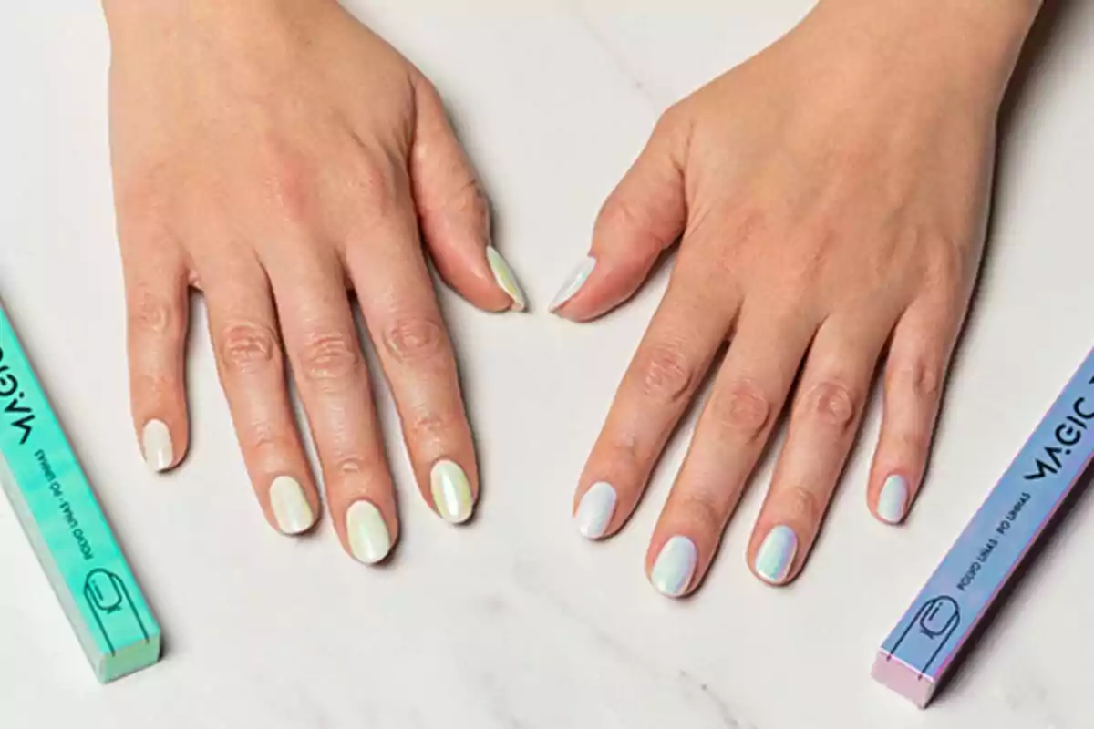 Manos con uñas pintadas en tonos pastel sobre una superficie blanca, junto a dos cajas de limas de uñas. Manos con uñas pintadas en tonos pastel sobre una superficie blanca, junto a dos cajas de limas de uñas.