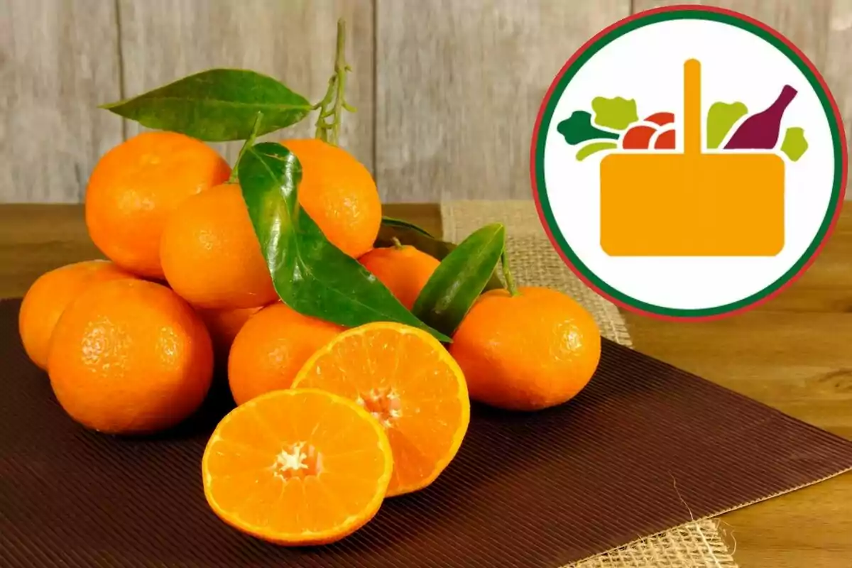 Mandarinas frescas con hojas verdes sobre una mesa junto a un logotipo de canasta de alimentos Mandarinas frescas con hojas verdes sobre una mesa junto a un logotipo de canasta de alimentos