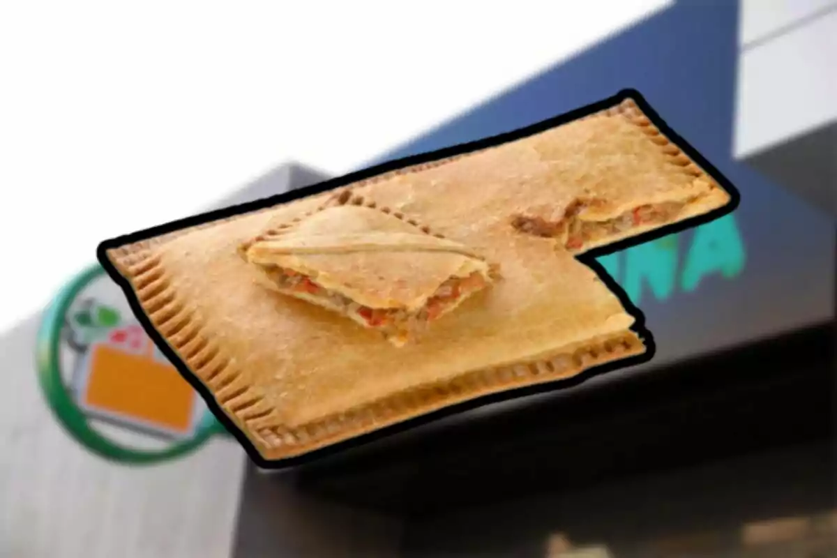 Empanada rectangular con relleno de carne y vegetales frente a un letrero de tienda Empanada rectangular con relleno de carne y vegetales frente a un letrero de tienda